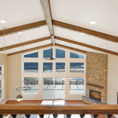 Living Room With Stained Ceiling Beams Tall Window Opening And Large Fireplace