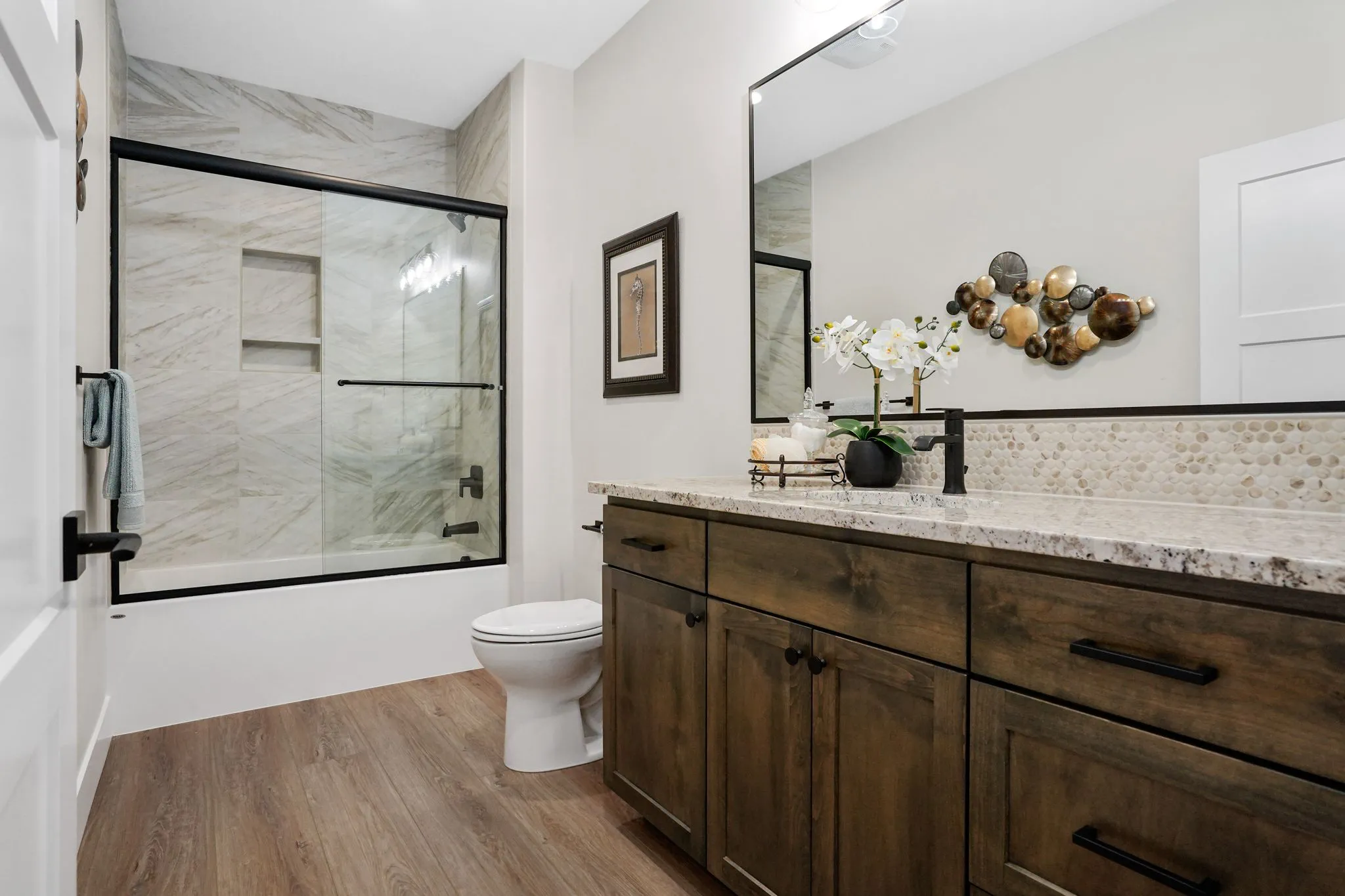 Bathroom With Dark Stained Cabinets And Large Mirrors And Ceiling High Tile Work