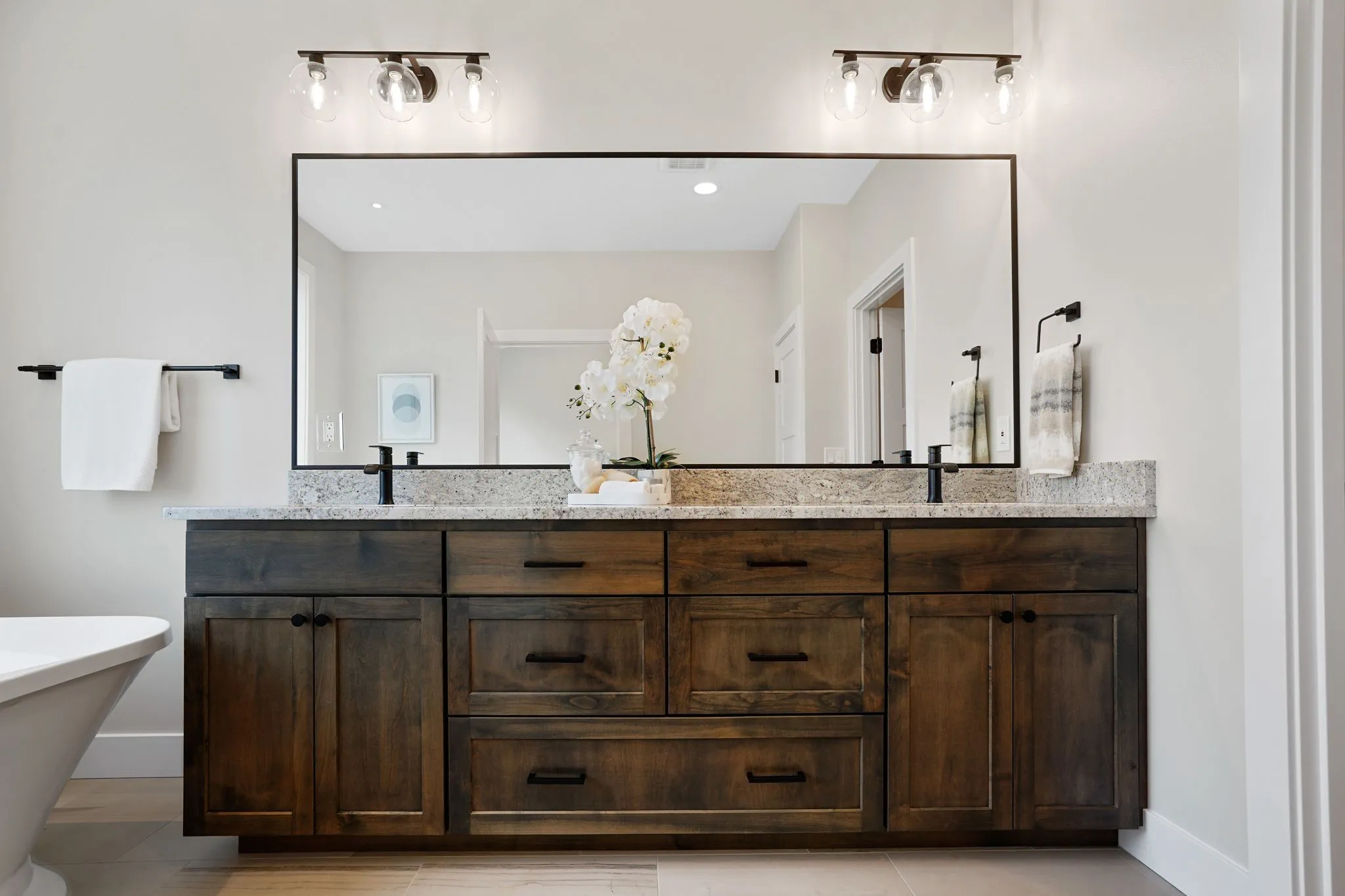 Primary Bathroom Dark Stain Custom Cabinet And Large Mirror And Vanity Lights