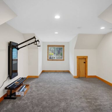 Bonus room with dark carpet with clear stain wood trim