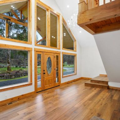 Entry surrounded with large windows with clear stain wood trim