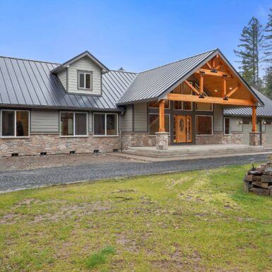 Exterior front large sprawling cabin looking home with mixture of metal stone wood and glass