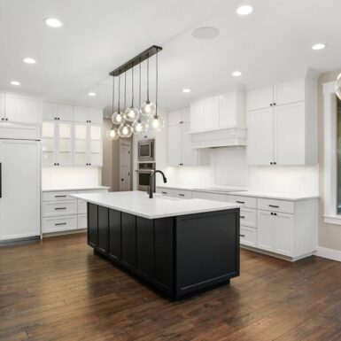 beautiful kitchen with mixture of dark and light cabinets and pendant lights above kitchen island