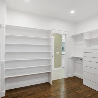 primary bedroom walk in closet with custom cabinets